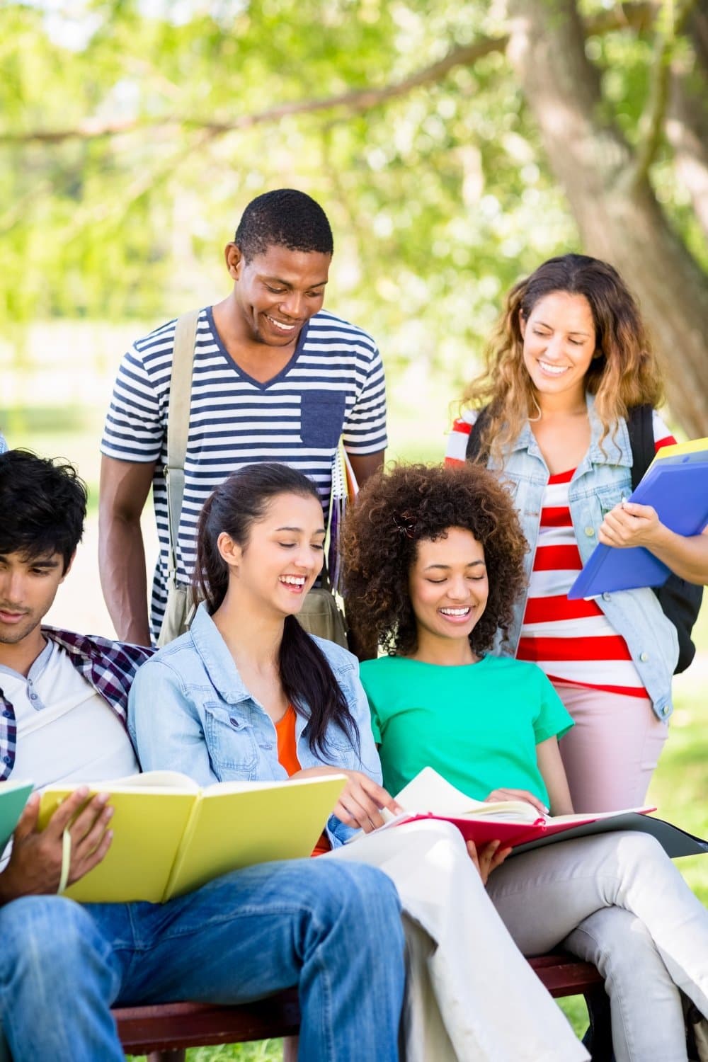 Happy diverse group of students studying and laughing in library
